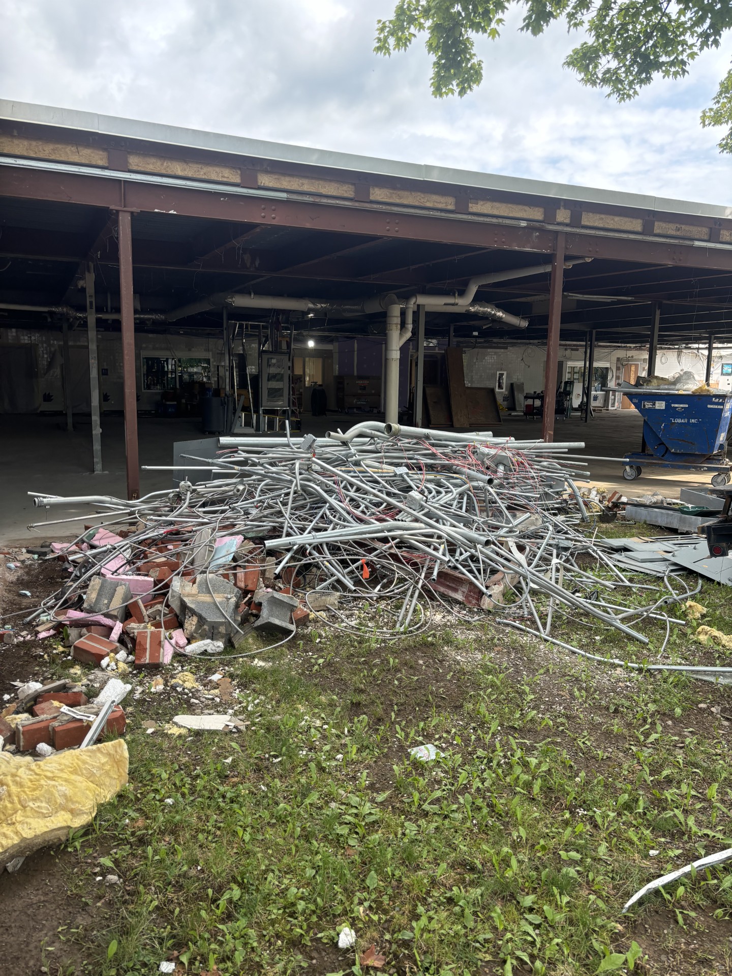 Pile of metal conduit, brick and construction debris outside a building under demolition
