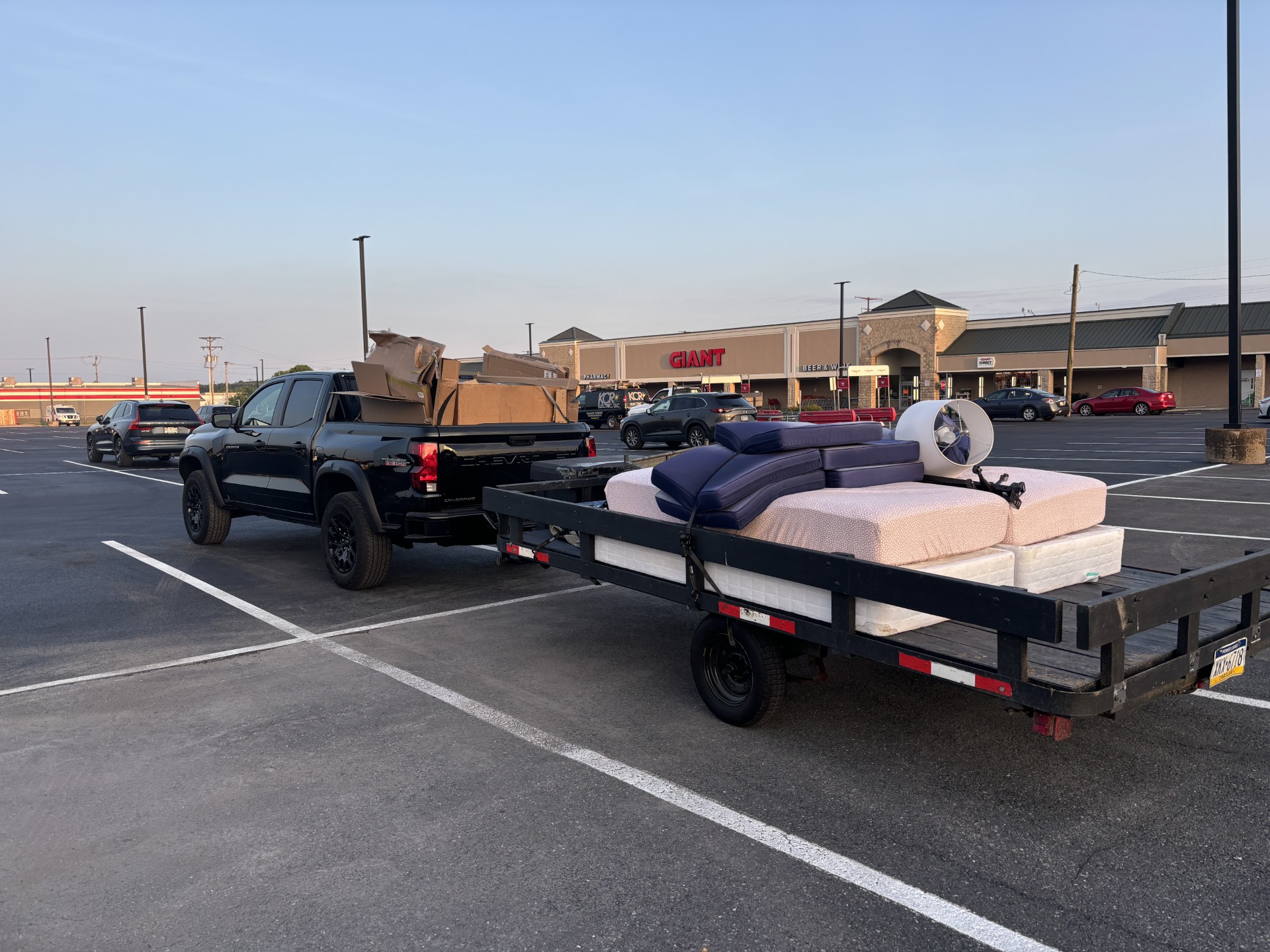 Truck and trailer loaded with a sectional couch and mattresses in a parking lot
