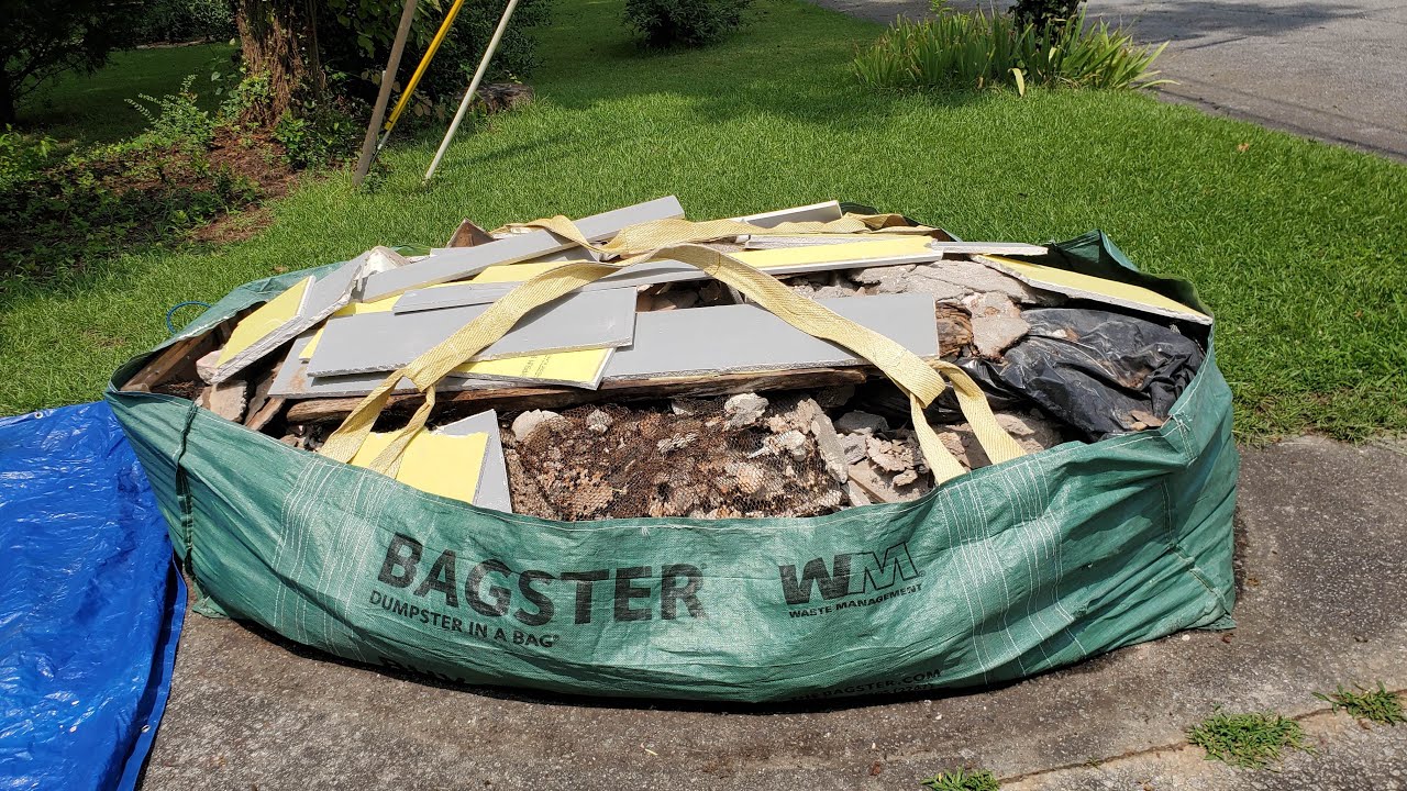 Bagster bag filled with drywall, tile and construction debris on a driveway